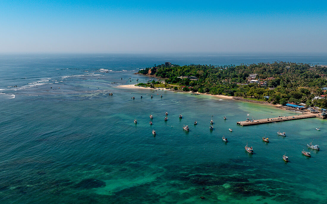 Fischerboote im klaren Wasser mit Riff und Wellen in Sri Lanka