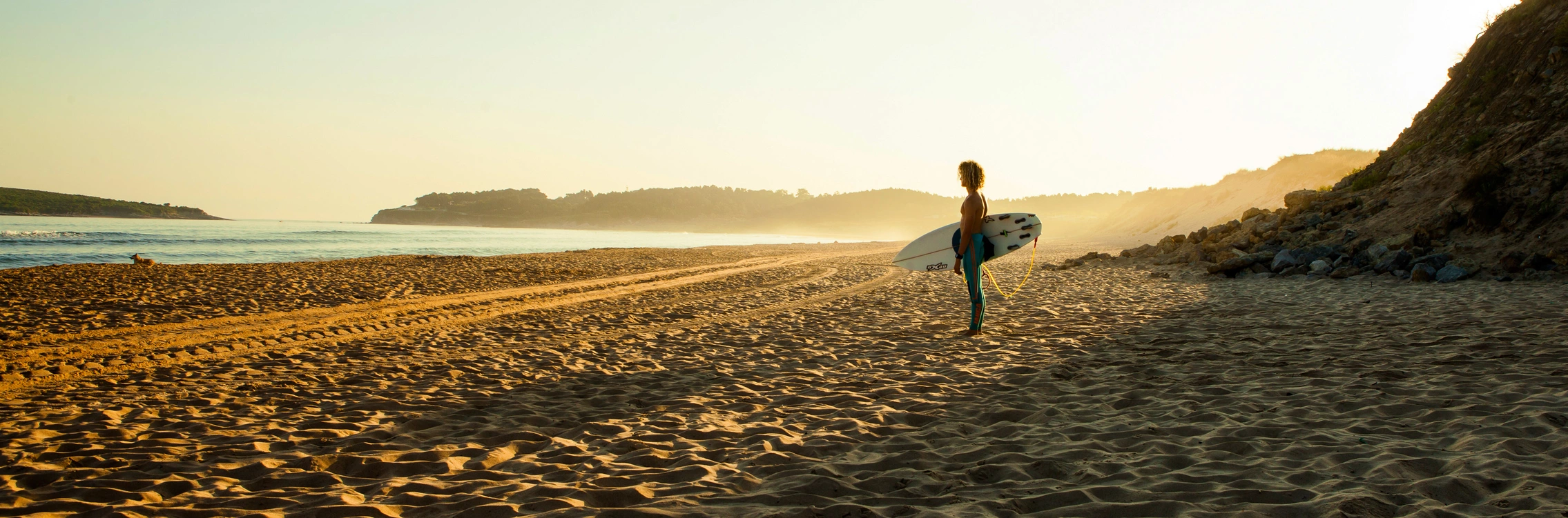 surfer standing with surfboard at spanish beach