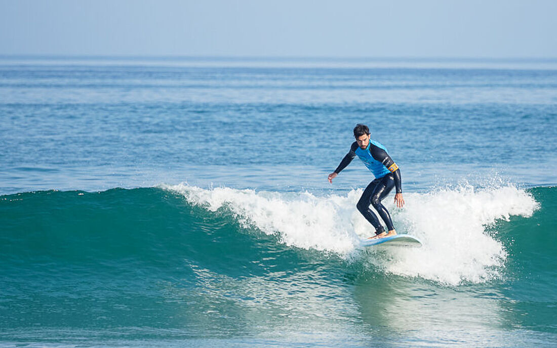 Surfer surft im Surfkurs eine gr&uuml;ne Welle