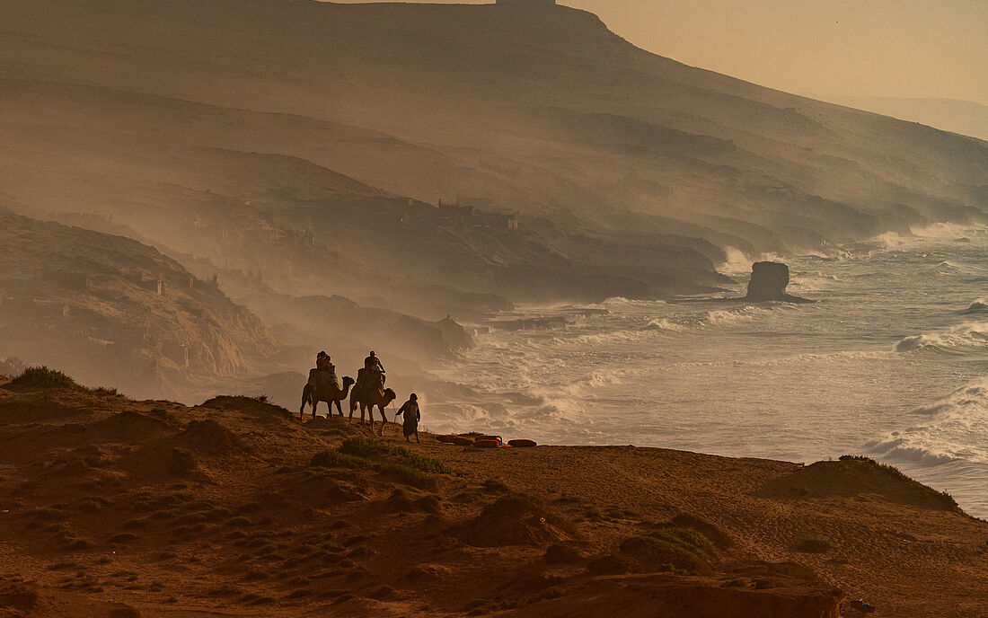 Mountains, camels, sea, and the golden glow of dusk.