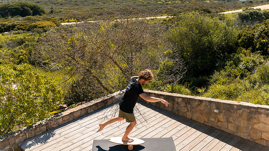 Mann steht einbeinig auf Balance Board mit Rolle Mann steht einbeinig auf Balance Board mit Rolle