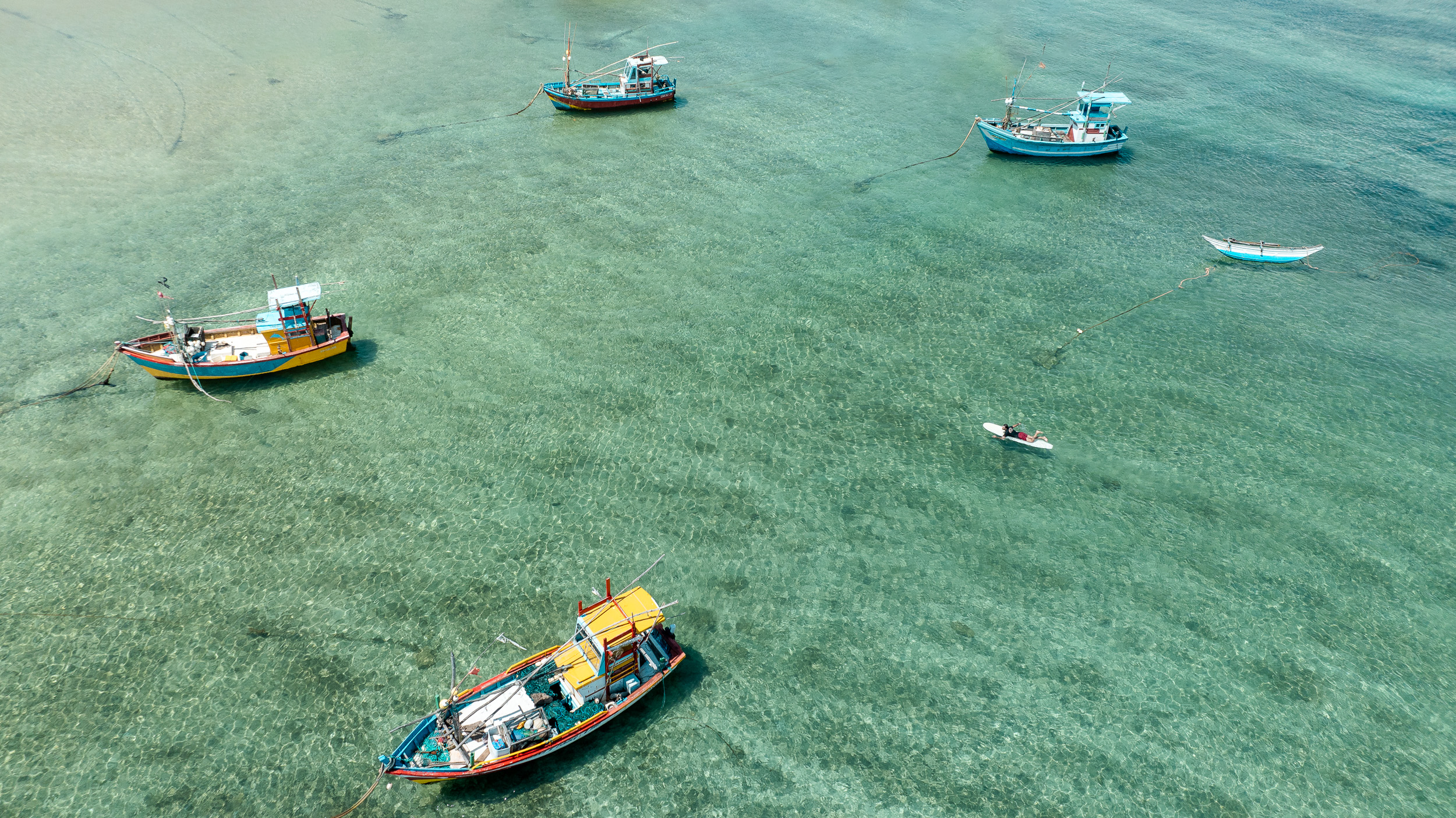 Surfer paddles through fishing boat